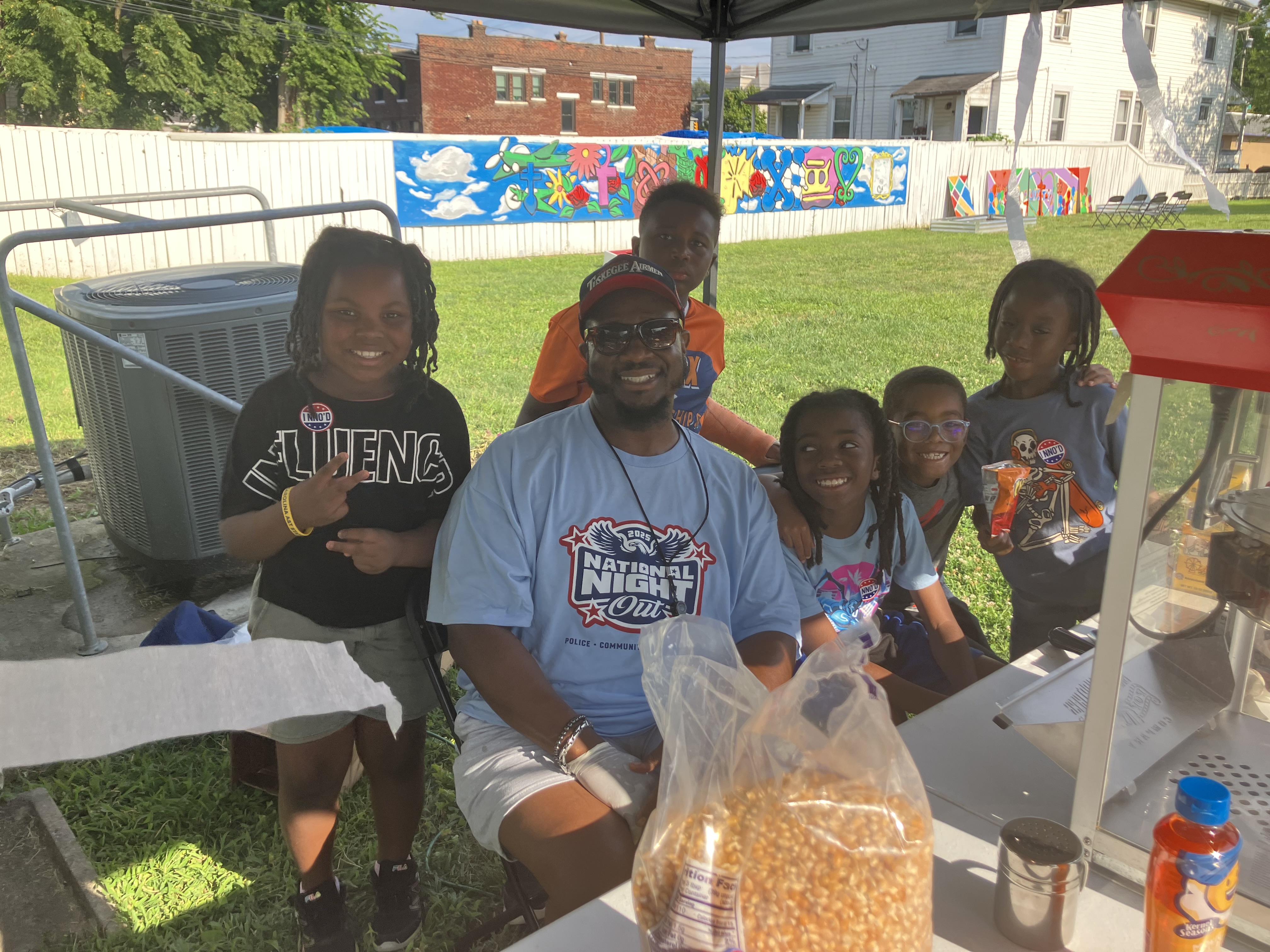 NNO Volunteer operating a popcorn stand surrounded by smiling children